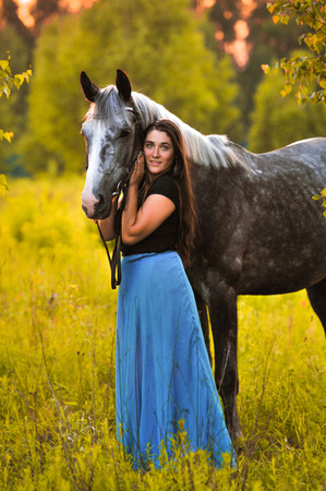 Woman and grey horse in summer timeの写真素材