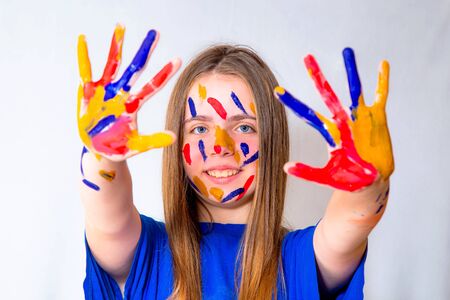 A young beautiful long-haired girl teenager in a blue T-shirt is engaged in her hobby for drawing...