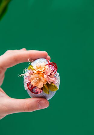 spring easter card. A bouquet of yellow tulips on a green background, and in the hand an Easter egg.の写真素材