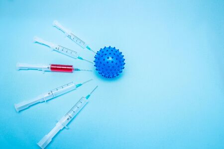 On a blue background lies a ball in the form of a coronavirus infection, around which there are...