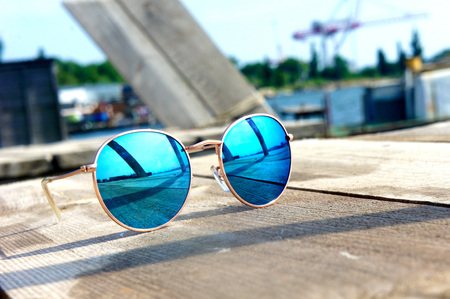 fashionable mirror glasses with blue glasses on the sun lie on a wooden floor rest trip reflected in...