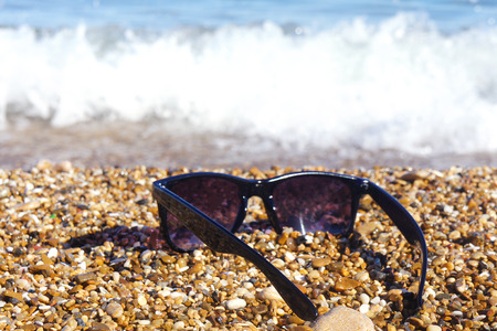 Plastic sunglasses against the background of sea stones.の写真素材