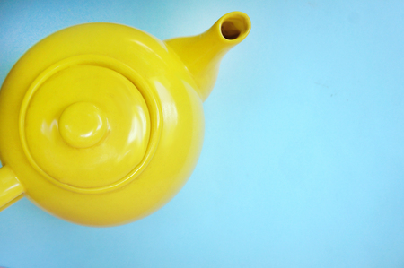 teapot on pastel blue background in modern design concept. yellow ceramic teapot . top view.の写真素材