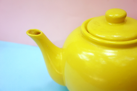 teapot on pastel blue pink background in modern design concept. yellow ceramic teapot . top view.の写真素材