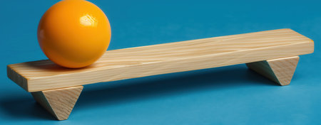 Wooden plank with orange sphere on blue background represents balance and simplicity in design.の写真素材