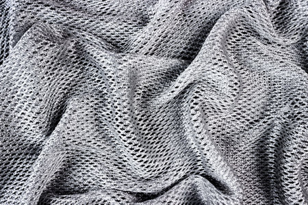 Silver fabric background folded with wavy folds.の写真素材