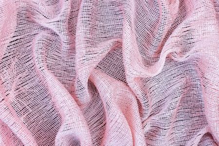 Pink shiny fabric background folded in wavy folds.の写真素材