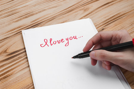 Female hand with a red marker and the inscription I love you on paper. The concept of Valentine's day, declarations of love, relationships.の写真素材
