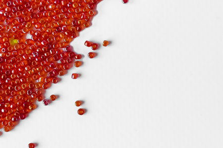 Scattered pile of red beads on a white background. Space for text. top view.の写真素材