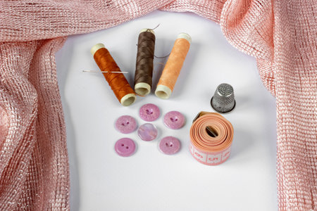 Sewing accessories: skeins of thread, buttons, fabric, thimble, needle and a centimeter on a white background. Needlework concept.の写真素材