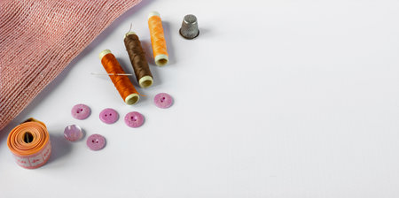 Accessories for sewing: coils of threads, buttons, thimble, pin, needle and centimeter on a white background. Space for text.の写真素材