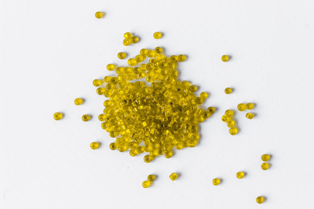Scattered pile of yellow beads on a white background. top view.の写真素材