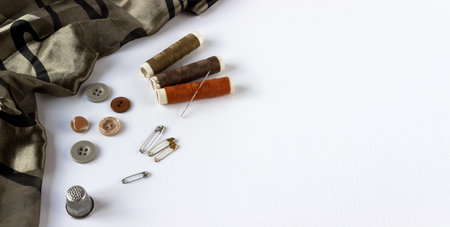 Accessories for sewing: coils of threads, buttons, thimble, pin, needle and centimeter on a white background. Space for text.の写真素材