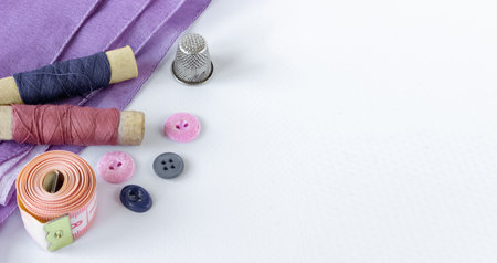 Accessories for sewing: coils of threads, buttons, thimble and centimeter on a white background. Space for text.の写真素材