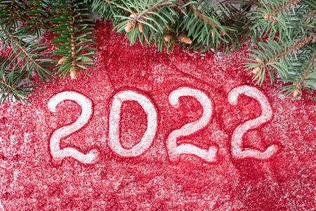 Inscription 2022 on a red background with spruce branches. The concept of New Year and Christmas....