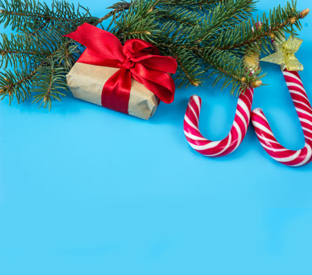 Gift boxes with red bows, caramel sticks and fir branches on a blue background. copyspace. Christmas and New Year concept. postcard.の写真素材