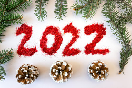 Inscription 2022 with spruce branches on a white background. The concept of New Year and Christmas. postcard.の写真素材