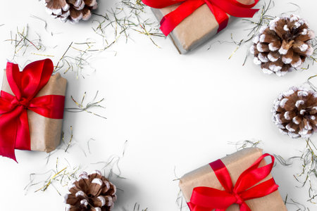 The frame of Christmas decorations gift boxes with red bows, pine cones on a white background. postcard. copyspace. flat lay. top view.の写真素材