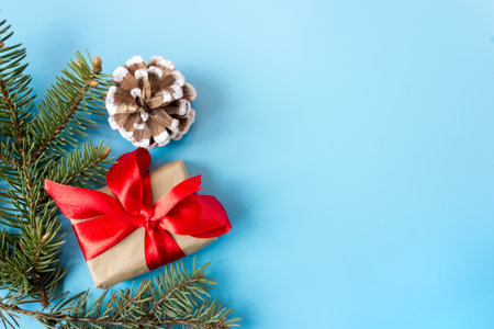 Gift boxes with red bows, pine cones and fir branches on a blue background. copyspace. flat lay. top view. Christmas and New Year concept.の写真素材