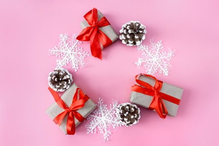 Christmas and New Year mockup on pink background. Frame made of snowflakes, cones and gift boxes. view from above. flat lay. copyspace.の写真素材