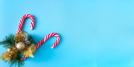 Spruce branch with Christmas decorations and caramel staffs on a blue background. Banner. postcard. The concept of New Year holidays. copyspace.の写真素材