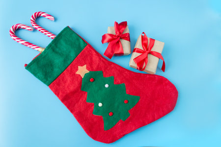 Christmas sock with gift boxes and caramel staffs on a blue background. postcard. The concept of Christmas and New Year.の写真素材
