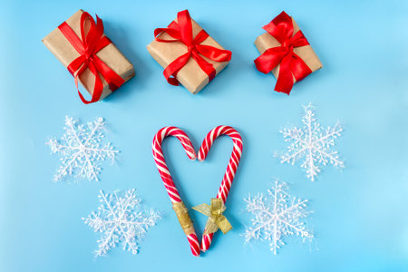 Gift boxes with snowflakes and caramel sticks in the shape of a heart on a blue background. postcard. The concept of Christmas and New Year.の写真素材