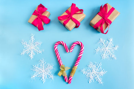Gift boxes with snowflakes and caramel sticks in the shape of a heart on a blue background. postcard. The concept of Christmas and New Year.の写真素材