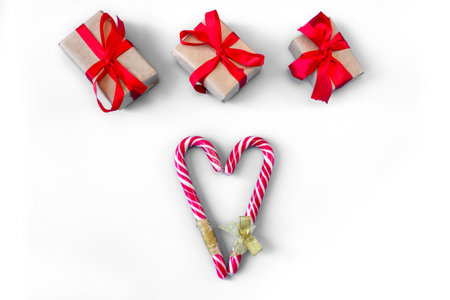 Gift boxes with caramel staffs in the form of a heart on a white background. postcard. The concept of Christmas and New Year.の写真素材