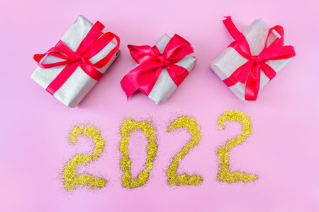Gift boxes with ribbon on a pink background and the inscription 2022. Top view. flat lay. Christmas and New Year concept.の写真素材