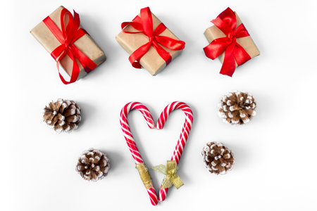 Gift boxes with pine cones and caramel sticks in the shape of a heart on a white background. postcard. The concept of Christmas and New Year.の写真素材