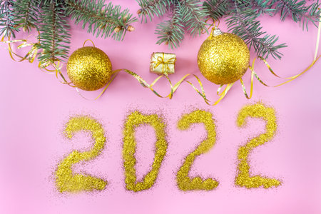 Christmas and New Year's layout on pink background. Postcard with a fir branch and toys. top view. flat lay. copyspace. Inscription 2022.の写真素材