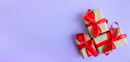 Gift boxes with a red bow on a violet background. Banner. copyspace. flat lay. top view. The concept of any holiday.の写真素材