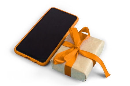 Gift box with orange tape with a smartphone on a white background. Holidays and sales concept.の写真素材