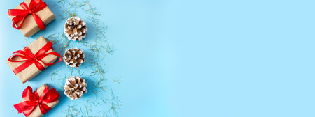 Gift boxes with red bows and pine cones on a blue background. Banner. copyspace. flat lay. top view. The concept of any holiday.の写真素材