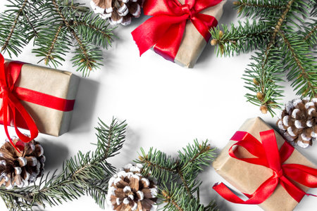The frame of Christmas decorations gift boxes with red bows, pine cones and spruce branches on a white background. postcard. copyspace. flat lay. top view.の写真素材