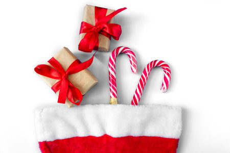 Santa Claus hat with caramel staffs and gift boxes on a white background. postcard. The concept of Christmas and New Year.の写真素材