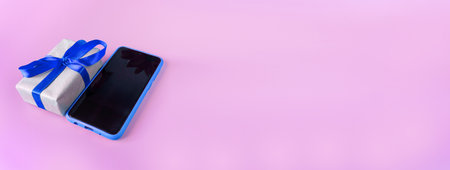 Blue smartphone with gift box on a pink background with place for text. Banner. postcard. copyspace.の写真素材
