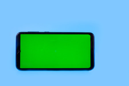 Smartphone in a horizontal position with a green screen on a blue background. Chrome key. Mock up.の写真素材