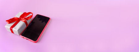Red smartphone with gift box on a pink background with place for text. Banner. postcard. copyspace.の写真素材