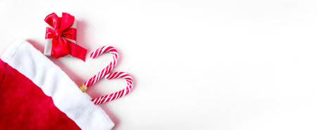 Santa Claus hat with gift box and caramel staff on a white background. flat lay. top view. postcard. Banner. Christmas and New Year concept.の写真素材
