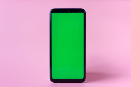 Smartphone in a vertical position with a green screen on a pink background. Chrome key. Mock up.の写真素材