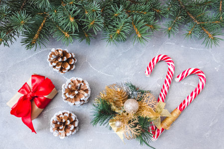 Festive gift box with spruce branches, caramel staves and pinecone on concrete background. The concept of New Year and Christmas. flatlay. postcard.の写真素材