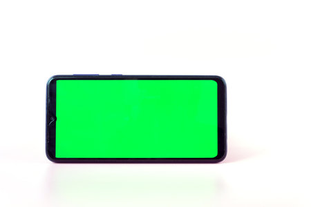 Smartphone in a horizontal position with a green screen on a white background. Chrome key. Mock up.の写真素材