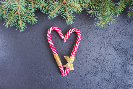 Caramel staffs in the form of a heart with spruce branches on concrete background. flat lay. top...