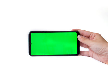 The woman's hand holds the smartphone in a horizontal position with a green screen on a white background. Chrome key. Mock up.の写真素材