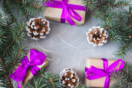 The frame of Christmas decorations gift boxes with pink bows, pine cones and spruce branches on concrete background. postcard. copyspace. flat lay. top view.の写真素材