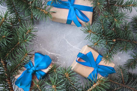 The frame of Christmas decorations gift boxes with blue bows and spruce branches on concrete background. postcard. copyspace. flat lay. top view.の写真素材