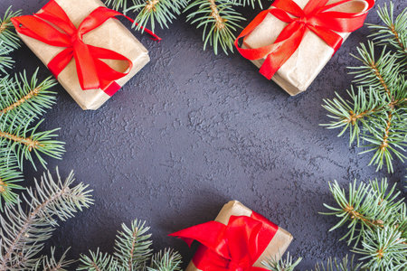 The frame of Christmas decorations gift boxes with red bows and spruce branches on concrete background. postcard. copyspace. flat lay. top view.の写真素材