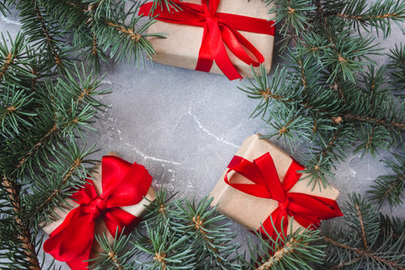 The frame of Christmas decorations gift boxes with red bows and spruce branches on concrete background. postcard. copyspace. flat lay. top view.の写真素材